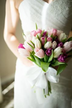 a bride holding a bouquet of pink and white tulips