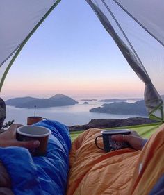 a person laying in a hammock holding a coffee cup