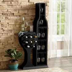 a wine rack with bottles and glasses on it in front of a brick wall next to a potted plant