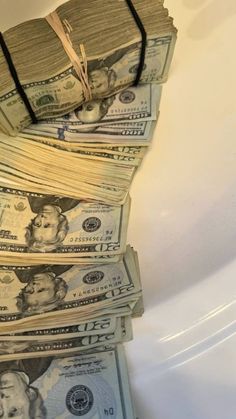 stacks of money sitting on top of each other in front of a bathtub filled with water