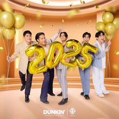 three men and two women holding balloons in the shape of numbers that spell out 205