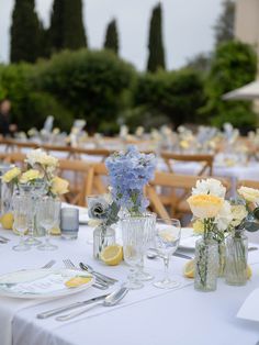 the tables are set with clear vases and white tablecloths, along with silverware