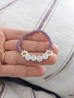 a hand holding a beaded bracelet with flowers on it and the word love spelled in small letters