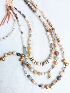 These two designs are big on interest and contrast, yet neutral, earthy, and everyday. A variety of gemstones including Fresh Water Pearls, Citrine, Prehnite, Opal, Jasper, Howlite, White Turquoise, Jade, several Agates, Quartz, Labradorite, and more. Mix these stones in with light and dark bone beads, Bodhi Beads, oyster shells, coconut, mixed metals, Czech, and seed beads in a variety of sizes, finish, and texture.  First, this extra chunky double layer necklace in contasting neutrals like car Earthy Agate Beaded Necklaces With Natural Stones, Agate Necklaces With Natural Stones For Layering, Everyday Bohemian Crystal Necklaces With Gemstone Beads, Earthy Natural Stone Jewelry, Nature-inspired Brown Jewelry With Gemstone Beads, Earthy Amber Necklace With Natural Stones, Natural Bohemian Jewelry For Everyday Wear, Bohemian Crystal Gemstone Necklaces For Everyday, Bohemian Crystal Necklaces With Gemstone For Everyday