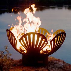 a fire pit sitting on top of a rock next to a body of water