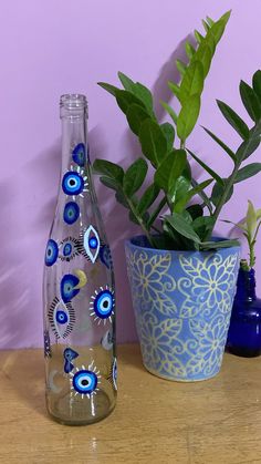 there is a plant in a vase next to a glass bottle with blue eyes on it