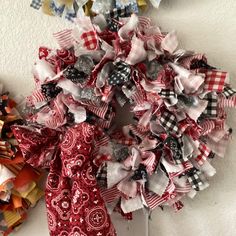 a red, white and black rag wreath on the wall next to a pair of scissors