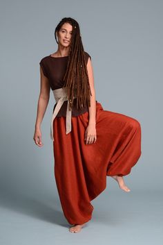 a woman with dreadlocks is standing in an orange skirt and brown shirt, posing for the camera