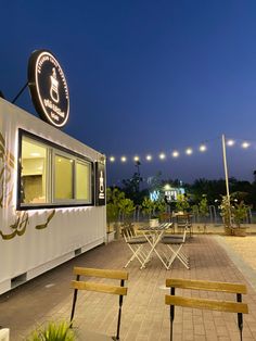 two wooden benches sitting in front of a food truck with lights on the side of it