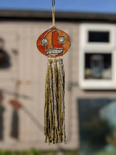 a wind chime hanging in front of a house with a face painted on it