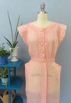 Stunning 1940's pink sleeveless dress. Pale pink seersucker slightly sheer fabric with vertical striping. Button down bodice with cute round yellow buttons, two side hip pockets, flared cap sleeves and fitted waist with button tab. Pull on. Gorgeous summery dress perfect for any occasion.  Fits like a medium but please double-check the measurements below to ensure the best fit for you. MEASUREMENTS--Taken with garment laying flat, in inches, doubled: Bust: 42" Waist: 32" Hips: 42" Shoulder to Waist: 16" Length: 42" Shoulder: 15" Fabric: Seersucker, plastic buttons Label/Era: 1940 | Bencone Condition: Excellent condition. Freshly laundered. Waist has an extra button hole that is hidden under the tab.  ★ Shop entire shop here: https://www.etsy.com/shop/retrosuzysvintage Instagram | retrosuzy Pink Sleeveless Vintage Dress For Spring, Pink Retro Dresses For Daywear, Pink Vintage Mini Dress For Summer, Retro Pink Vintage Dress For Daywear, Spring Sleeveless Pink Vintage Dress, Spring Vintage Sleeveless Pink Dress, Spring Pink Sleeveless Vintage Dress, Pink 1950s Vintage Dress For Summer, Pink 1950s Style Vintage Summer Dress