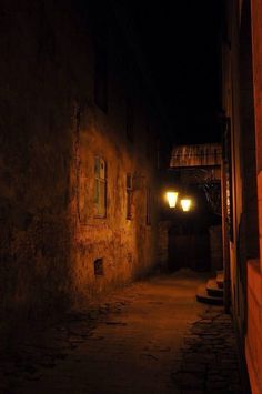 a dark alley way with two lights on the side and one light on the other