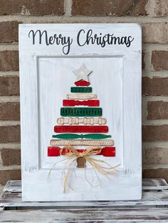 a christmas tree made out of books sitting on top of a wooden shelf in front of a brick wall