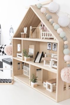 a wooden doll house sitting on top of a white floor