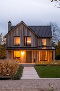 a house that is lit up with the sun shining through the windows and grass in front of it