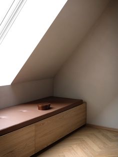 a wooden bench sitting under a window in a room with white walls and wood flooring