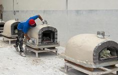 a man working on an outdoor pizza oven in the middle of snow covered flooring