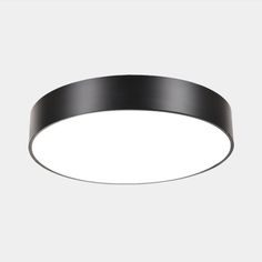 a black circular light fixture on a white wall