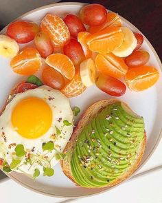 an avocado, oranges, and eggs are on a plate with bread