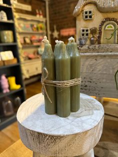 three green candles sitting on top of a wooden table in front of a store display