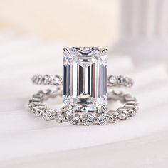 an emerald - cut diamond ring sits on top of a white surface with diamonds surrounding it