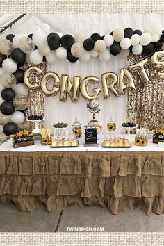 a table with balloons, sunflowers and confetti on it in front of a sign that says congrat