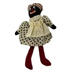 a black doll wearing a white dress and red socks with a hat on it's head