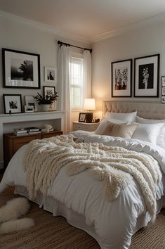 a bed with white sheets and blankets in a bedroom next to pictures on the wall