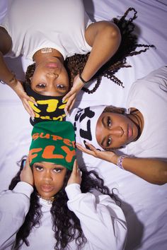 three young women laying on top of each other wearing matching scarves and head coverings