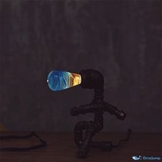 a small tripod with a blue and yellow object on it's head sitting in front of a dark background