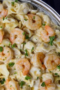 pasta with shrimp and parsley in a silver bowl on a black tablecloth, top view