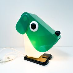 a green dog lamp sitting on top of a table next to a phone charger