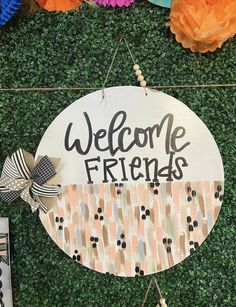 a welcome friends sign hanging on the side of a wall with paper flowers and streamers