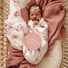 a baby wrapped in a pink blanket with a name tag on it's chest