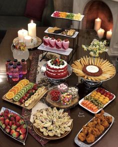 a table topped with lots of different types of desserts and pastries next to candles