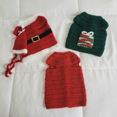 three crocheted christmas sweaters and hats are laying on a white bed sheet