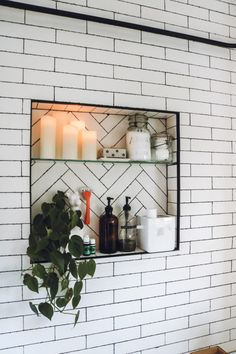 a shelf with candles, soaps and other items on it in front of a white brick wall