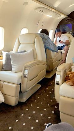 two people sitting in the back of an airplane with their feet up on the seats