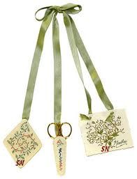 two tags with ribbons attached to them on a white background, one has a green ribbon and the other has a gold scissors