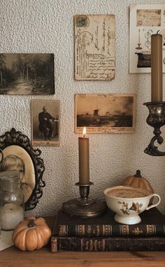 there is a candle that is on top of a table next to some books and pictures