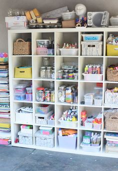 a large white shelf filled with lots of crafting supplies and storage bins on top of it