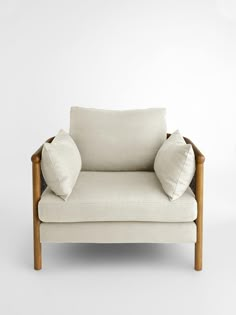 a white chair with two pillows on it's back and the seat upholstered