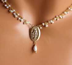 "This is a gold Miraculous Medal Pearl Choker Necklace for women. Absolutely elegant! This necklace is made with 2-3mm fresh water pearls on 24kt gold plated wire, a 14kt gold filled medium size Miraculous medallion 20x13mm at it's center with a Pearl drop. Necklace is adjustable 2\" with a spring clasp in back. Model is wearing a 14\"-16\" length. Comes nicely boxed, the perfect gift! Maybe ordered in 925 Sterling silver." Spiritual Gold Pearl Drop Necklace, Gold Spiritual Necklace With Pearl Drop, Spiritual Gold Pearl Necklace With Pearl Charm, Spiritual Gold Pearl Necklace With Charm, Gold Pearl Necklace With Spiritual Charm, Spiritual Gold Necklaces With Pearl Drop, Spiritual Gold Necklace With Pearl Drop, Gold Pearl Necklace As A Meaningful Gift, Catholic Jewelry Necklace