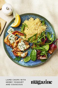 a blue plate topped with meat and veggies next to lemon wedges on top of a table