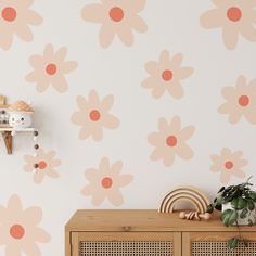 a wall with flowers painted on it next to a wooden cabinet and potted plant