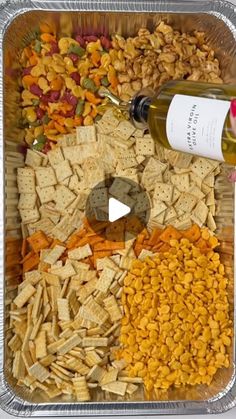 a container filled with lots of different types of food next to a bottle of wine