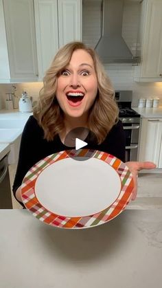 a woman holding up a plate with an open mouth in the middle of a kitchen