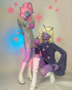 two women dressed in costumes posing for the camera with stars on the wall behind them