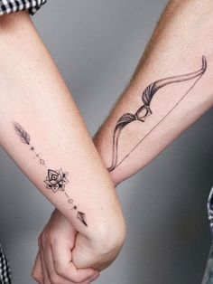 two people holding hands with tattoos on their arms, one has an arrow and the other has a bow