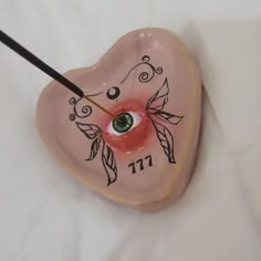 a pink heart shaped clock with an eye on it